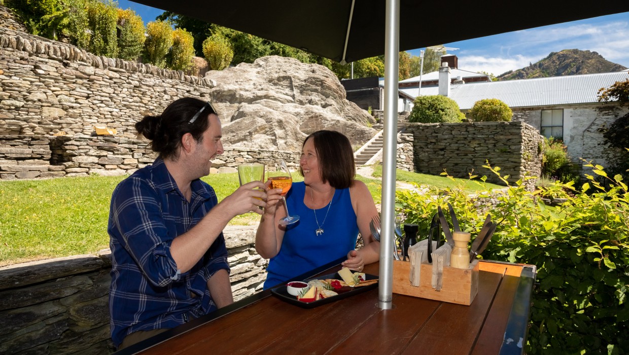 Historic stone wall behind diners on Buckingham Green, Arrowtown
